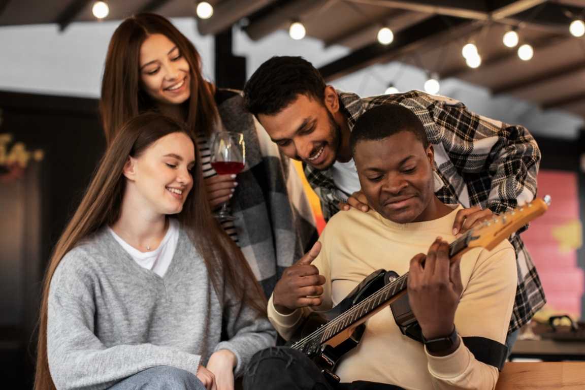 Imagen vibrante que muestra a un grupo de amigos divirtiéndose mientras uno de ellos toca la guitarra eléctrica, creando un momento musical alegre y relajado